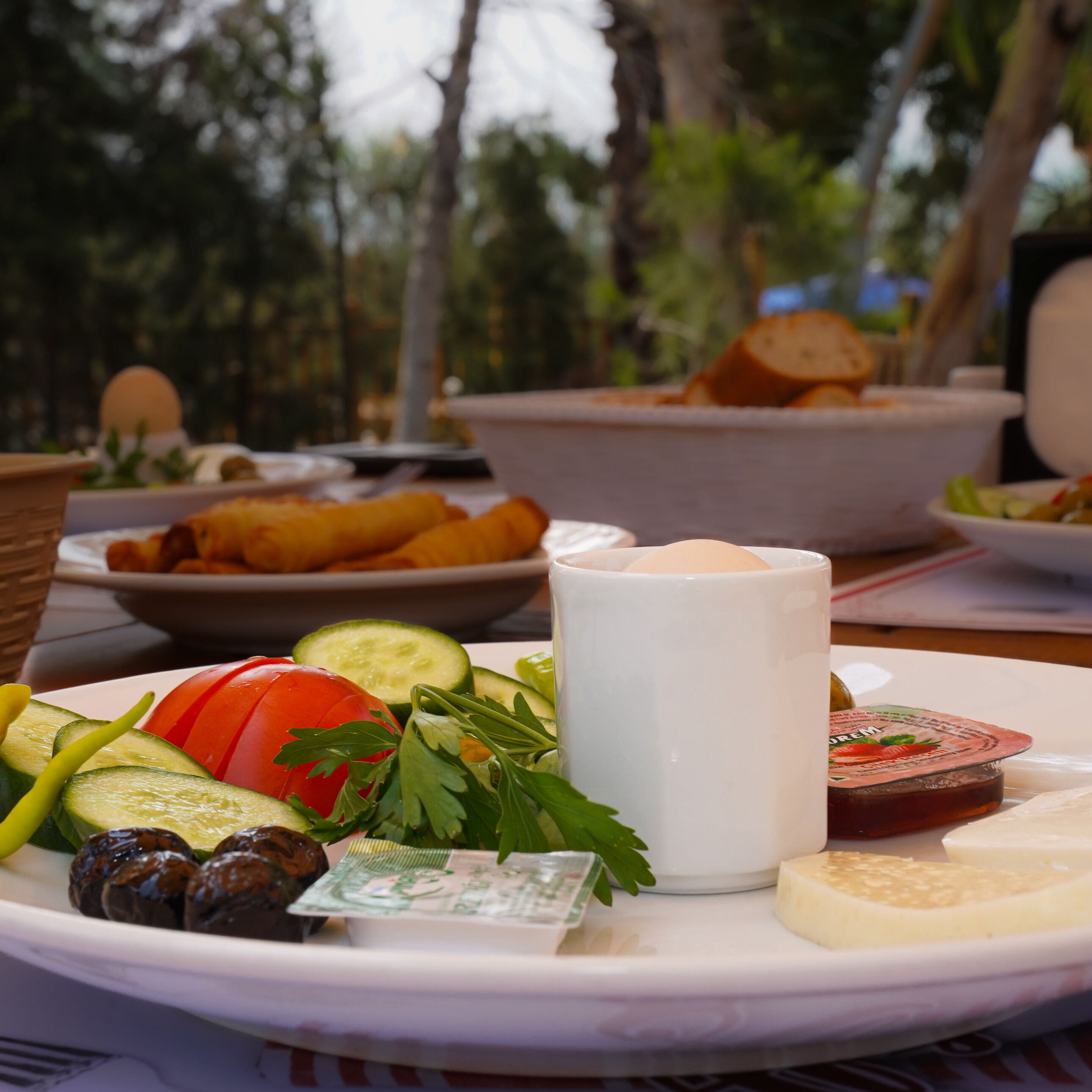 A table with a variety of foods including sliced cucumbers, tomatoes, cheese, and bread.