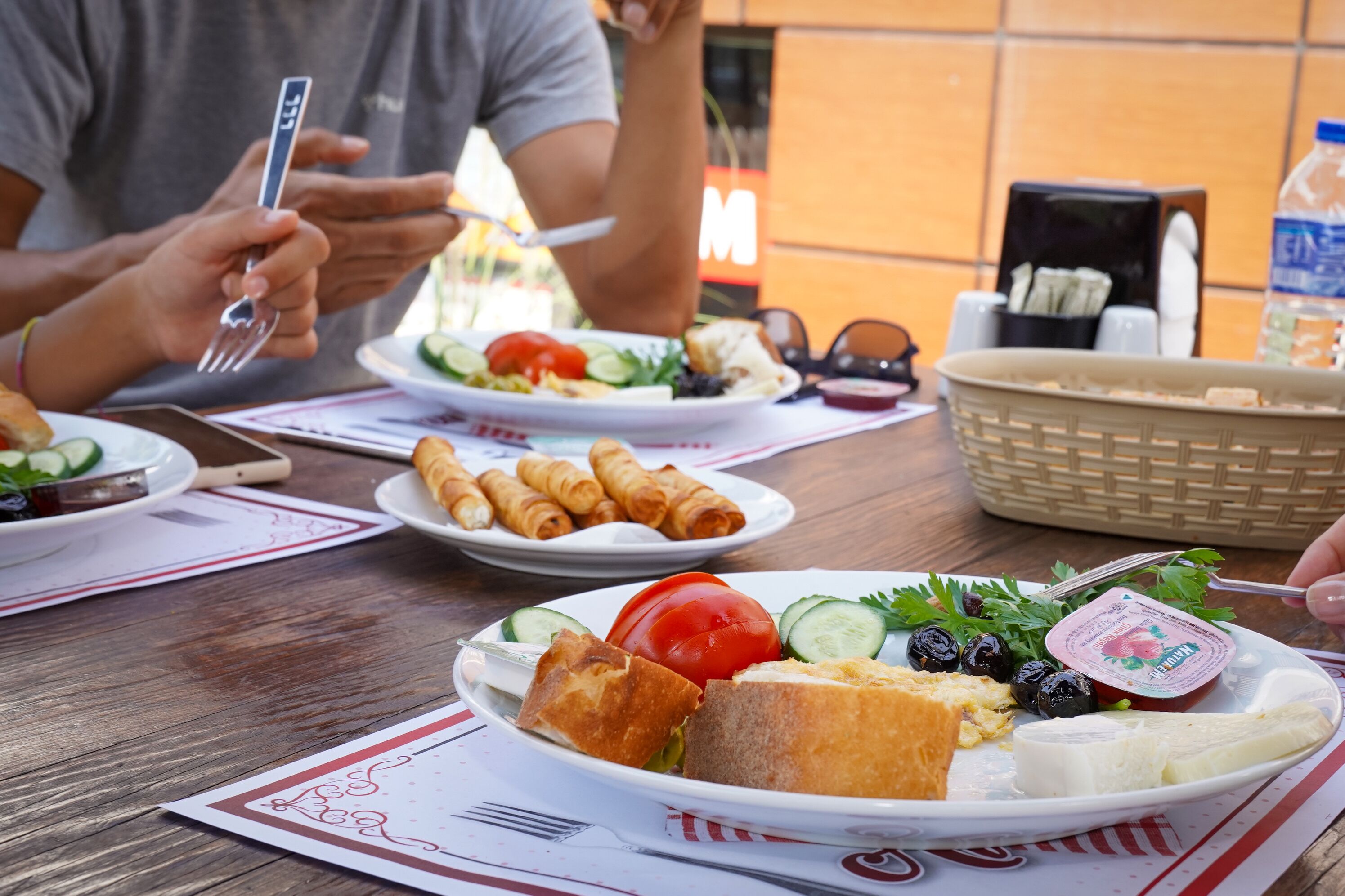 A dining table with plates of food, including a salad, bread, and cheese.