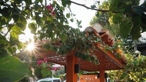 A wooden pergola with a sign reading "Nehr BOS Oda" surrounded by lush greenery and flowering plants. - Akyaka Nehir Butik Otel (Ula)