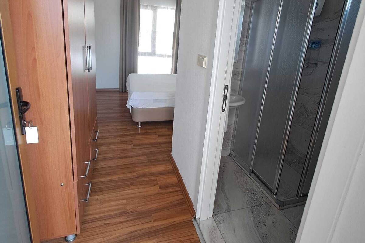 Quarto de hotel com armário de madeira, uma cama, área de chuveiro e vista para o exterior.