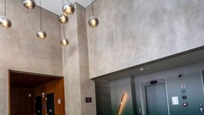 Eine Lobby mit modernem Design, mit Marmorboden, sechseckigen Sitzgelegenheiten und einem grünen Aufzug.
