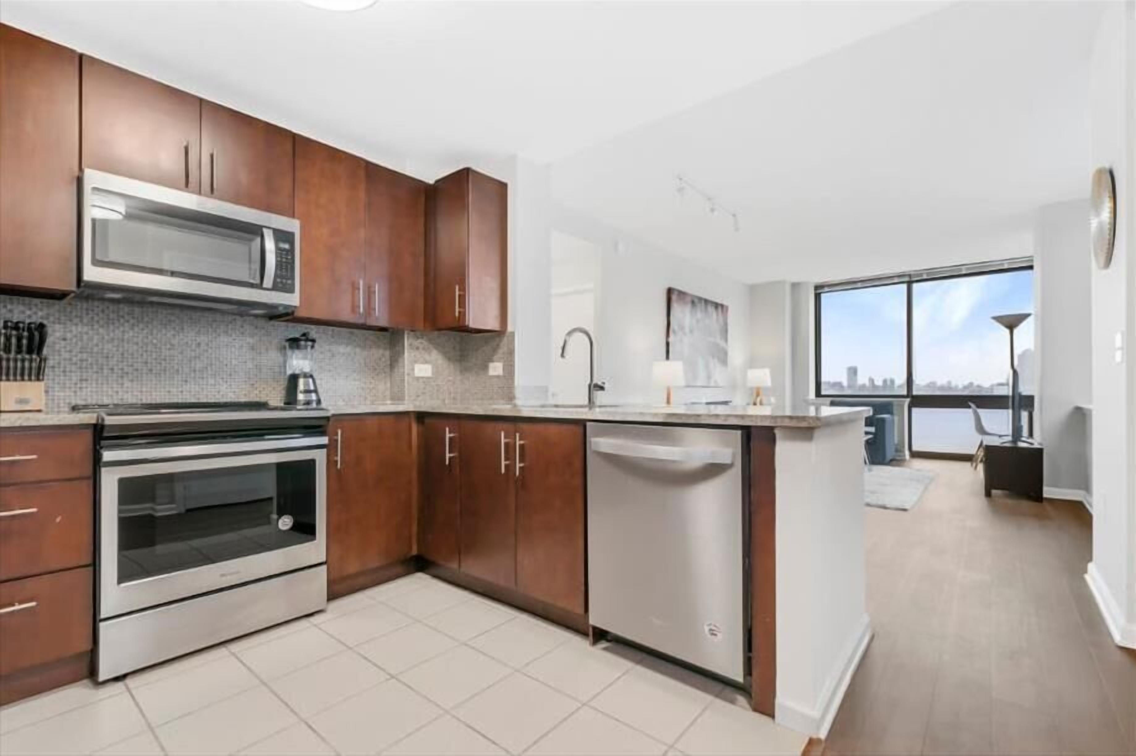A modern kitchen with stainless steel appliances, wooden cabinets, and a dishwasher.