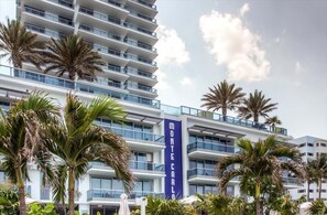 A modern hotel with multiple balconies and palm trees.
