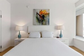 Ein Schlafzimmer mit einem großen Bett, zwei Nachttischen mit Lampen und einem Gemälde an der Wand.