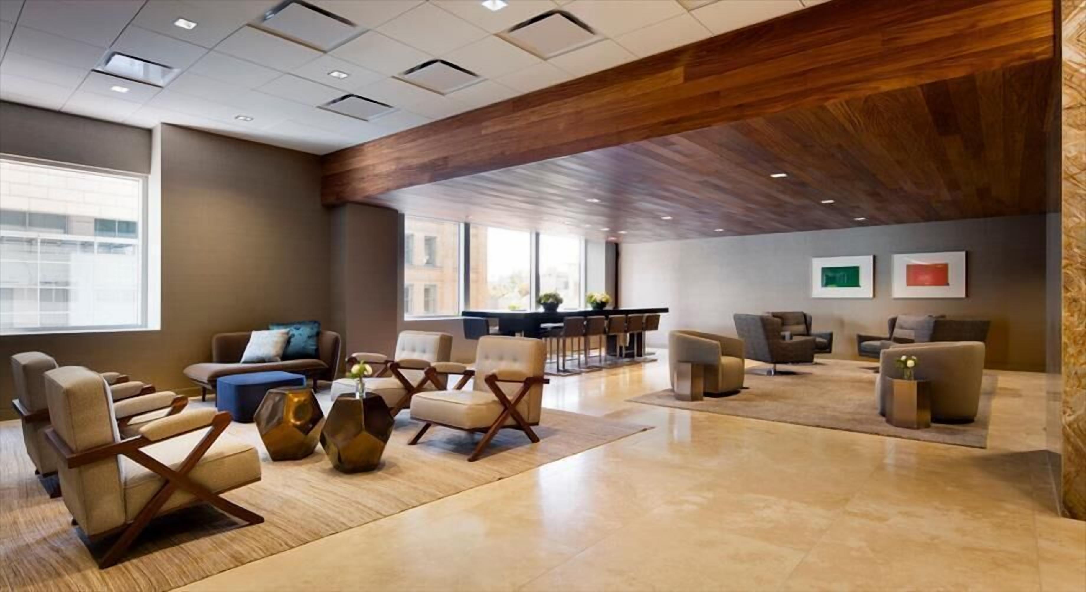 A spacious lobby with modern furniture, a wooden ceiling, and large windows providing natural light.
