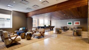 A spacious lobby with modern furniture, a wooden ceiling, and large windows providing natural light.