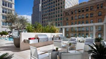 An outdoor patio with a barbecue area, seating, and a pool.