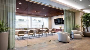 A modern conference room with glass walls, a large table, and several chairs.