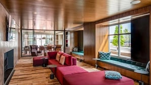 A modern living room with a red sofa, wooden flooring, and large windows offering a view of the outdoors. - Boston Pier 1 BR | Close to Airport | Workspaces (East Boston)