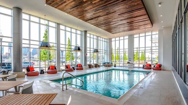 An indoor swimming pool with large windows, wooden ceiling, and seating areas. - Boston Pier 1 BR | Close to Airport | Workspaces (East Boston)