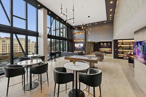 Ein moderner Aufenthaltsraum mit Billardtisch, Sitzgelegenheiten und einem großen Fernseher.