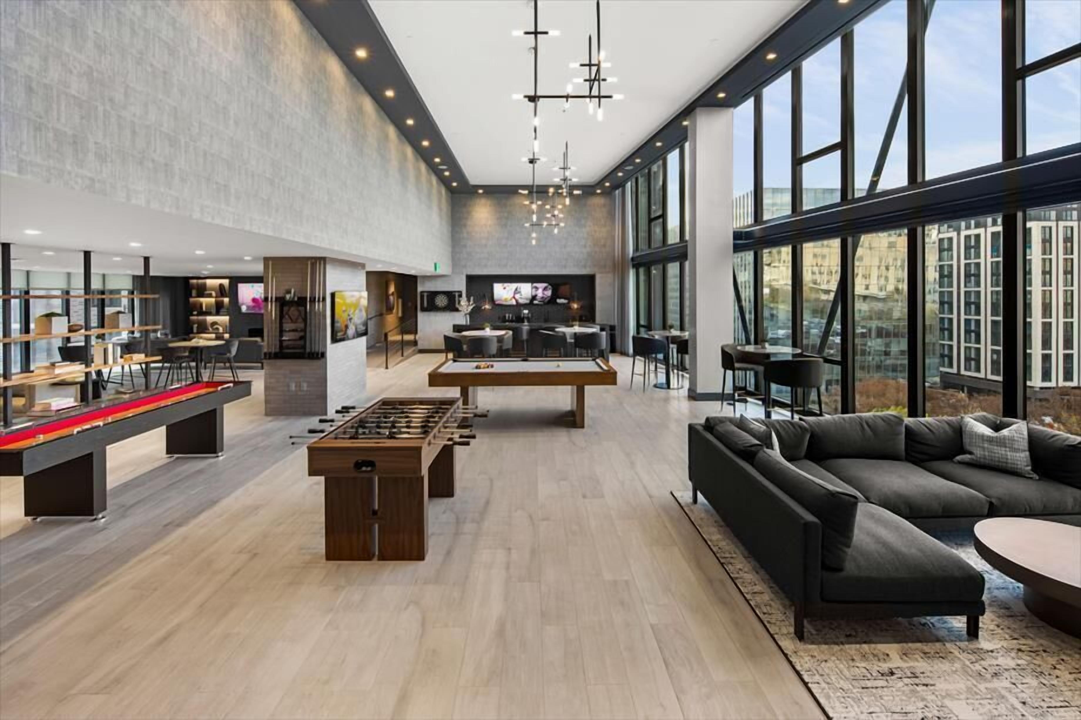Um espaço amplo e coberto com mesa de pebolim, sofá e mesa de bilhar.