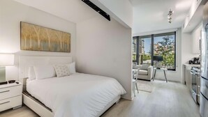 Een moderne slaapkamer met een groot bed, een nachtkastje en een kunstwerk aan de muur.