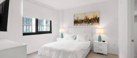 A modern bedroom with a large bed, white nightstands, and a cityscape painting on the wall.