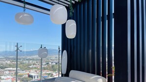 Una sala de estar moderna con un sofá blanco, ventanas amplias y lámparas esféricas colgantes.