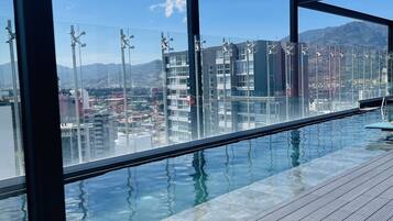 Una piscina infinita en la azotea con vistas despejadas al paisaje urbano y montañas al fondo.