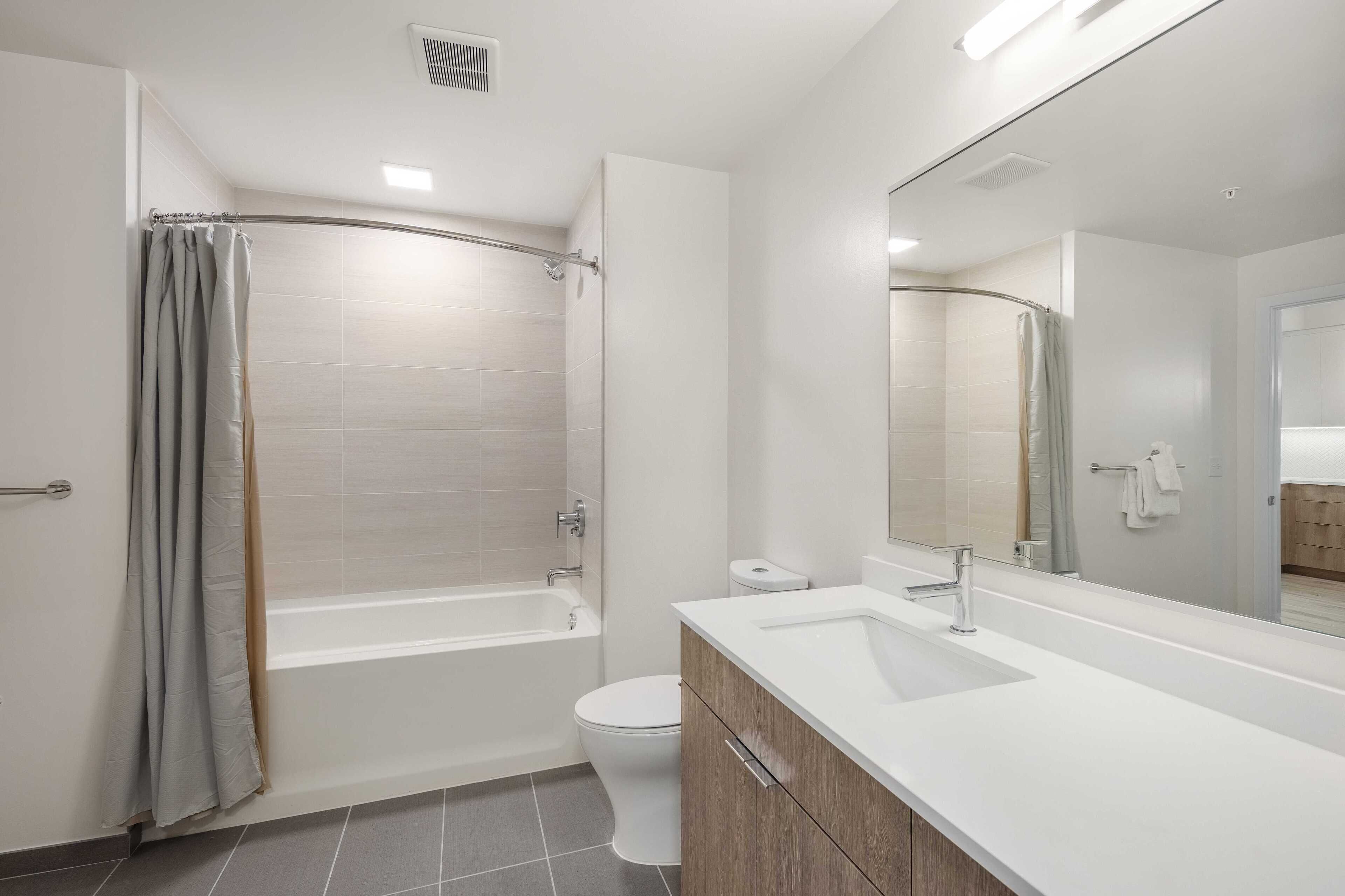 A modern bathroom with a bathtub, toilet, and vanity.