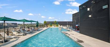 Uma piscina no terraço com água azul cristalina, cadeiras de descanso e guarda-sóis.