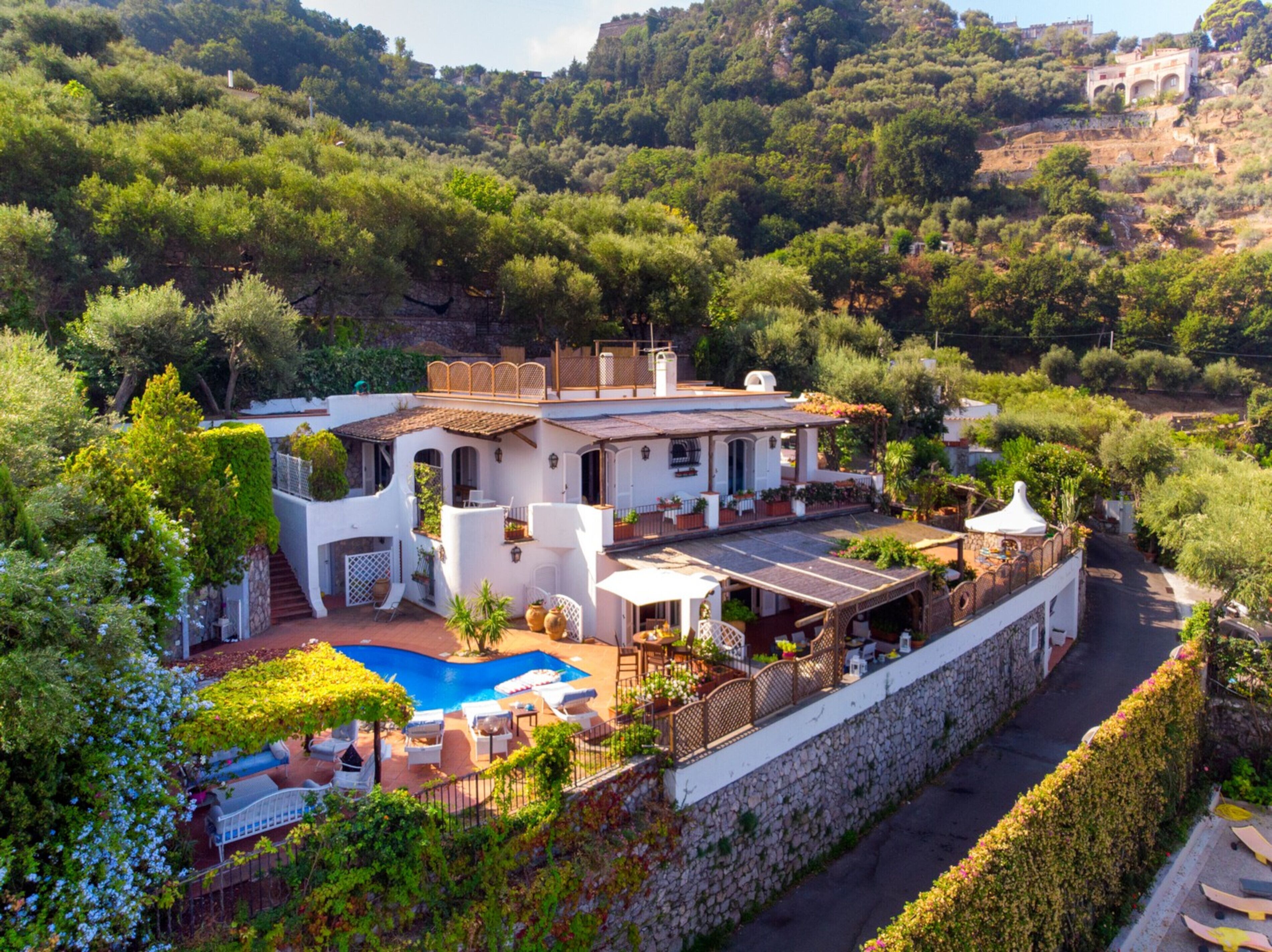 Uma villa com piscina, área de estar externa e parede de pedra.