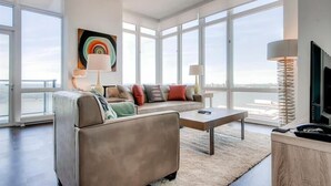 A modern living room with a sofa, coffee table, and a large window offering a view of the city.