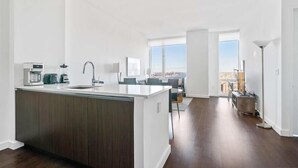 Une cuisine moderne dotée d’un îlot central, d’un coin repas offrant une vue agréable et d’un vaste espace de vie avec une grande fenêtre.