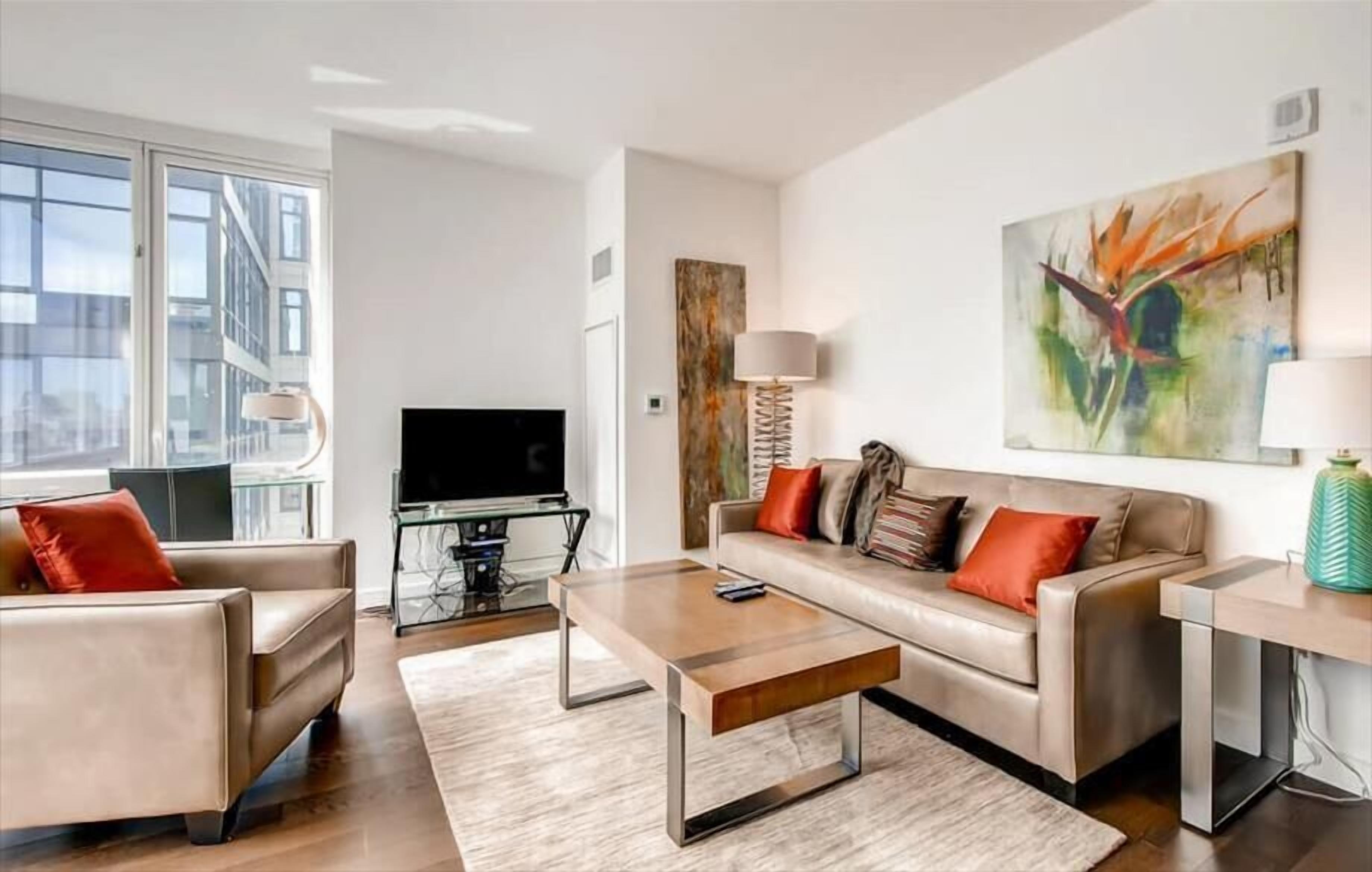 A modern living room with a sofa, armchairs, a coffee table, and a TV.