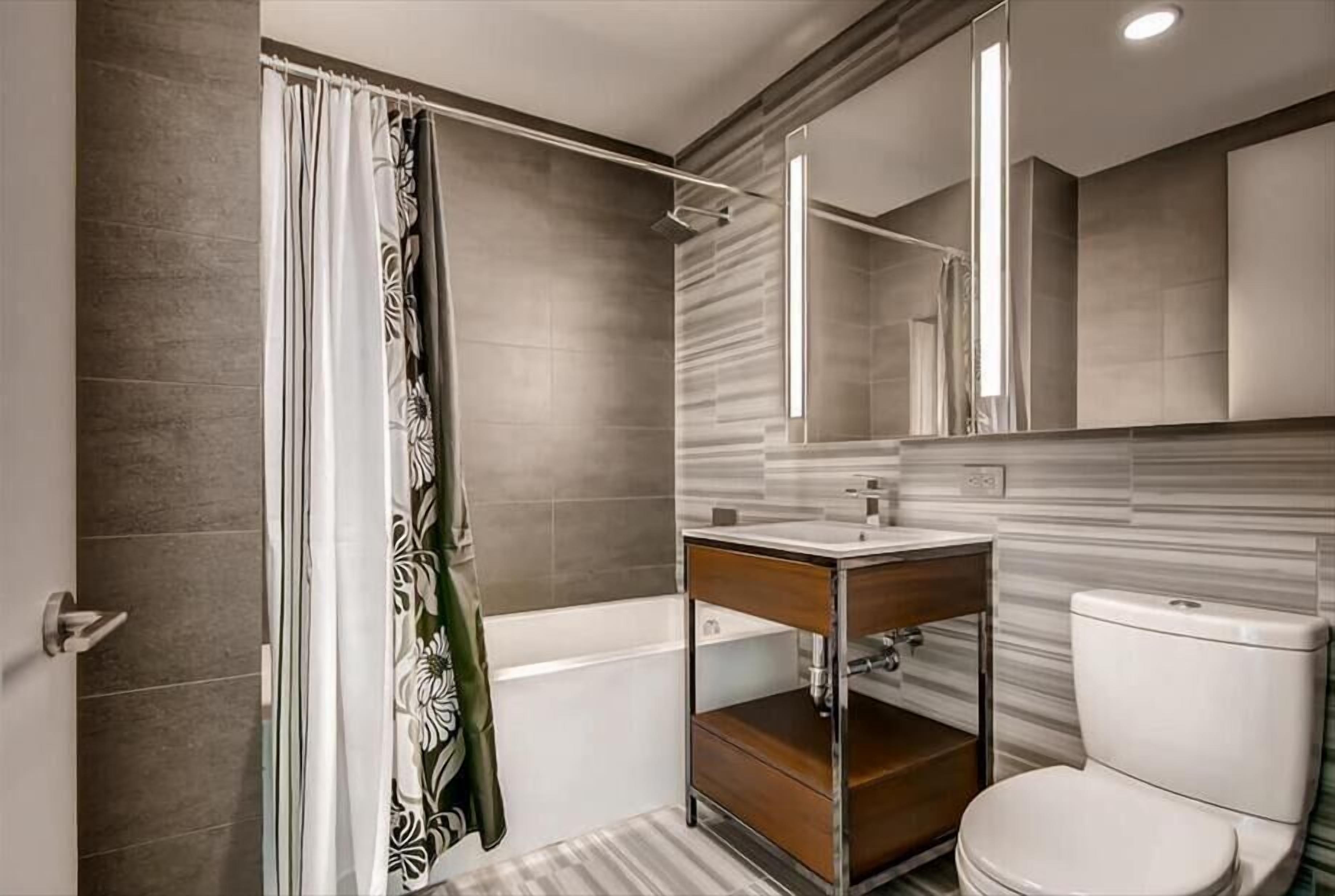 Ein modernes Badezimmer mit Badewanne, Toilette und Waschtisch mit Spiegel.