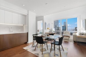 Una cocina moderna con una mesa de comedor de vidrio, armarios de madera y vistas a la ciudad a través de amplias ventanas.