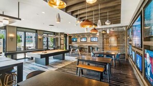 Un espacio interior moderno con mesa de billar, comedor y bar.