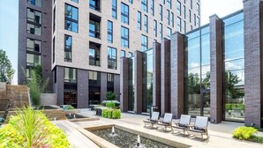 A modern building with a courtyard featuring a water feature and seating areas.