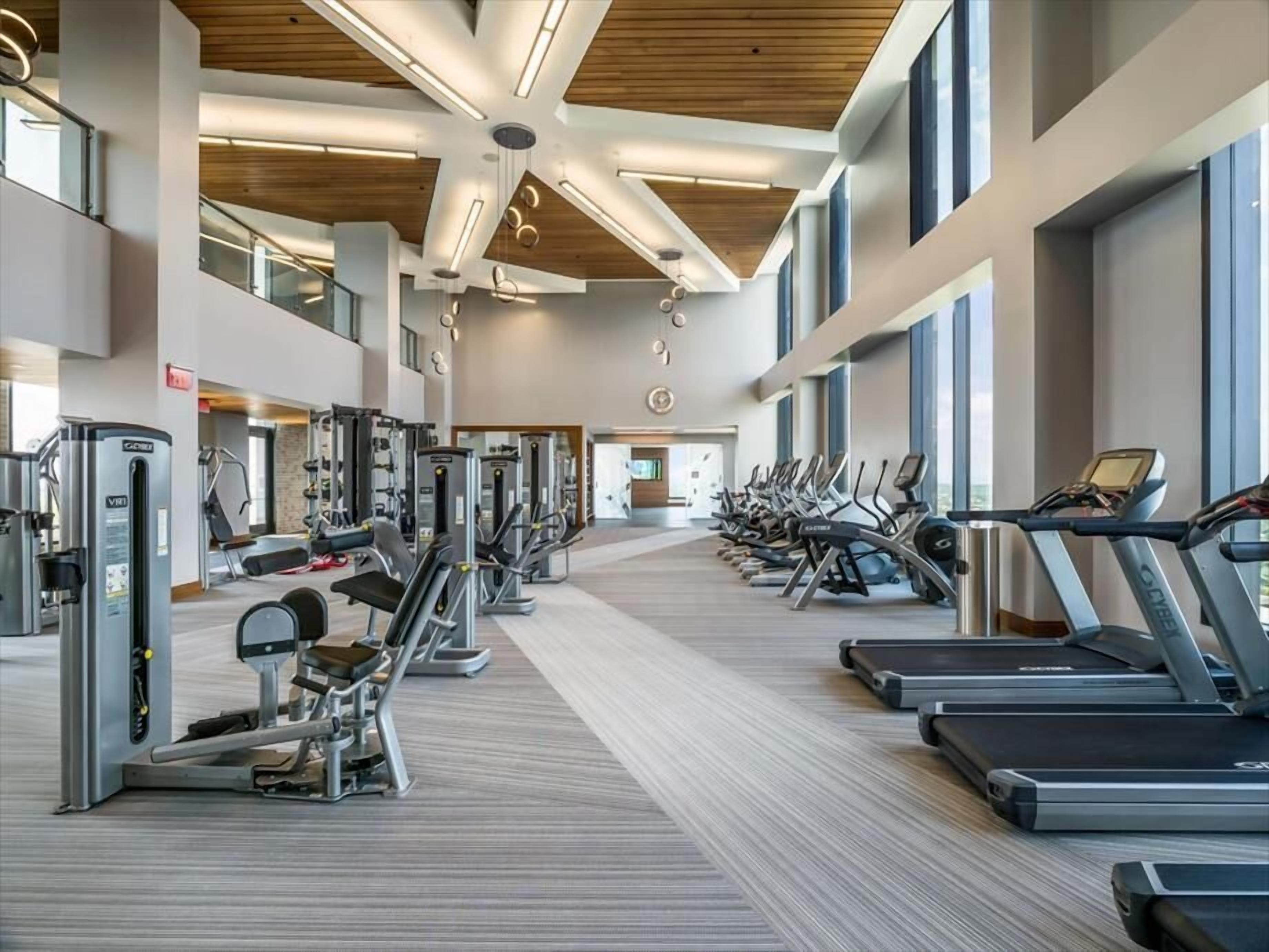 A modern gym with treadmills, elliptical machines, and weight equipment.