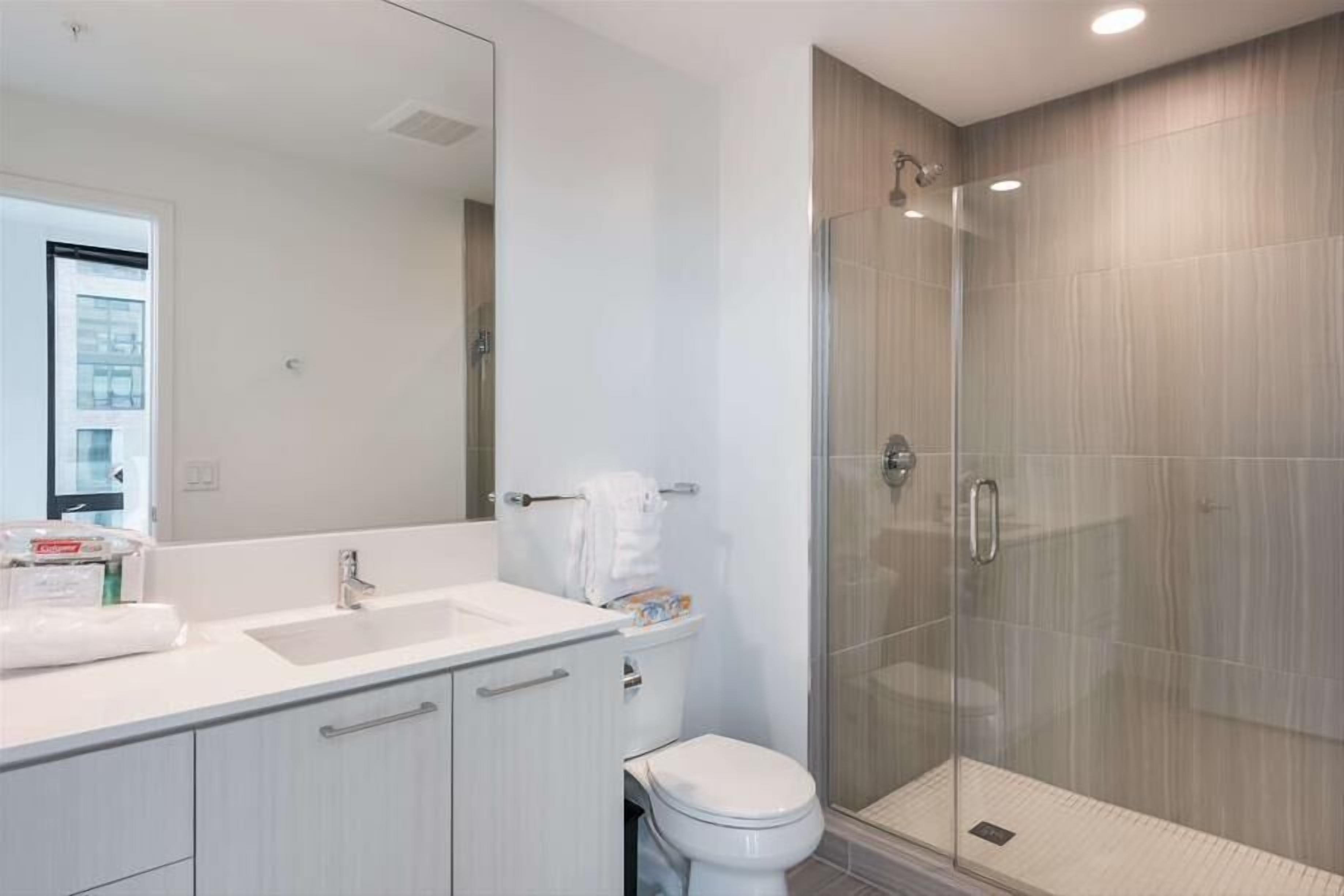 A modern bathroom with a glass shower enclosure, a white sink, and a toilet.