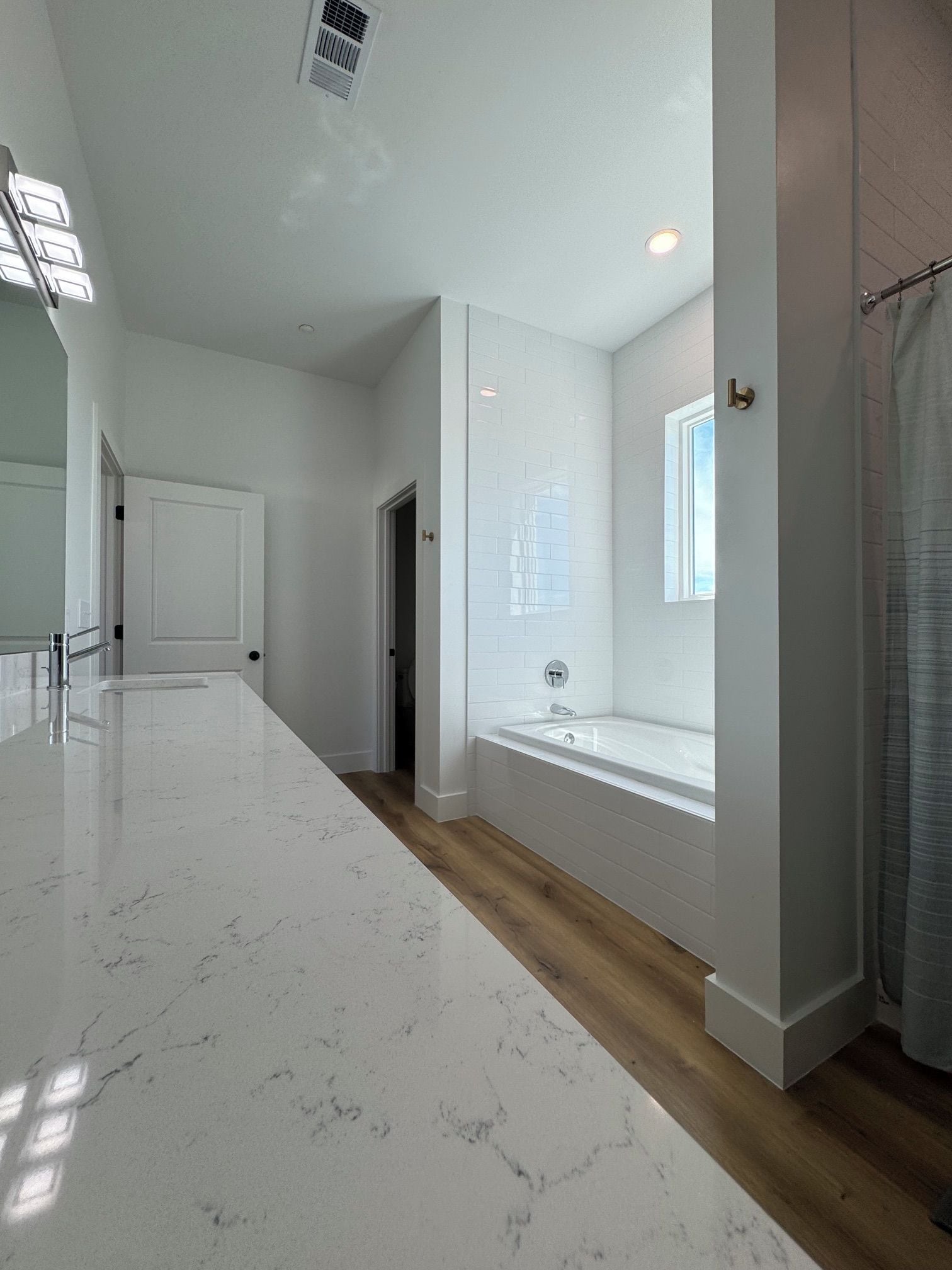 A modern bathroom with a large mirror, a bathtub, and a shower area.