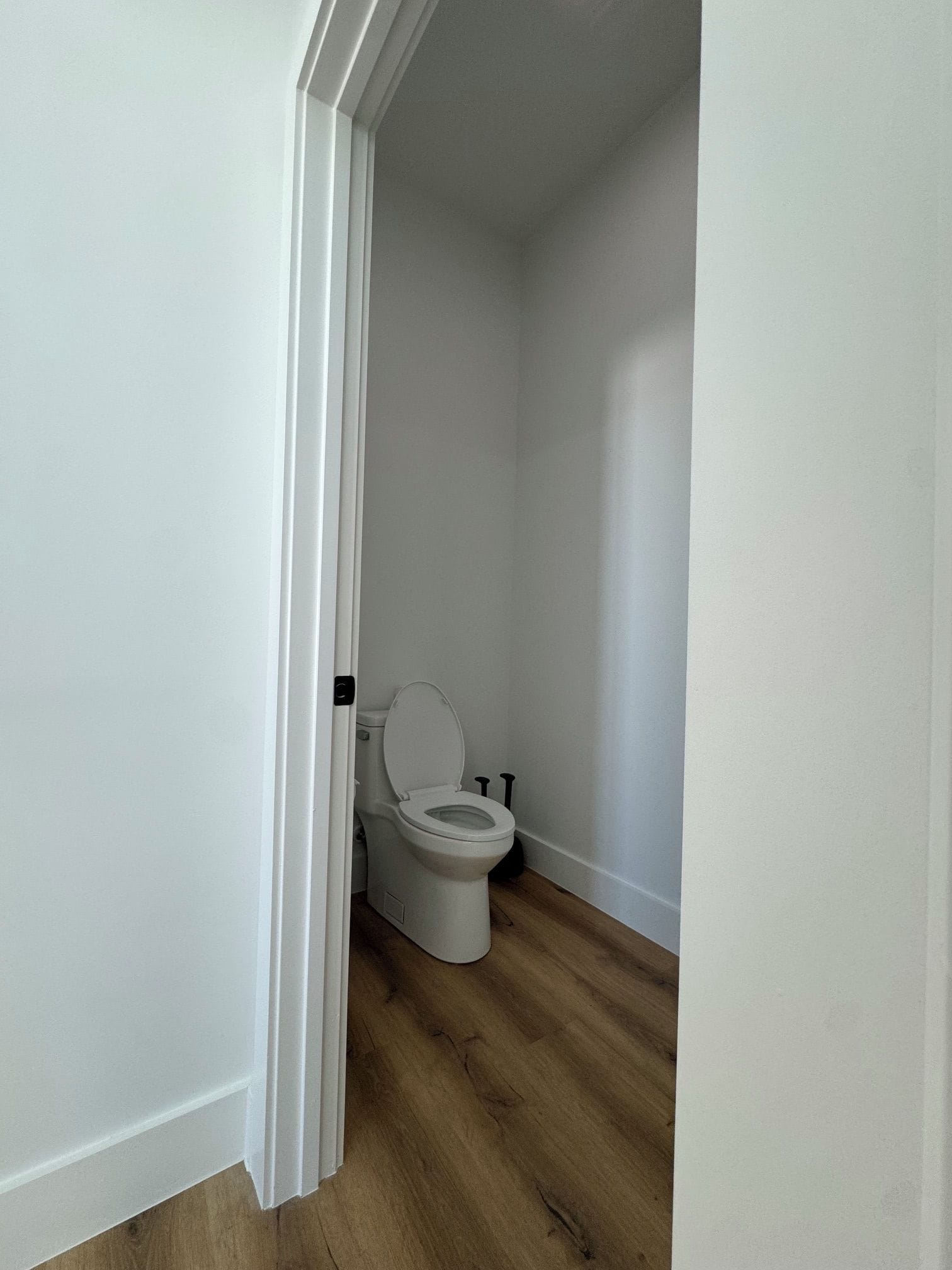 Une petite salle de bain propre, avec des toilettes blanches et un plancher en bois.