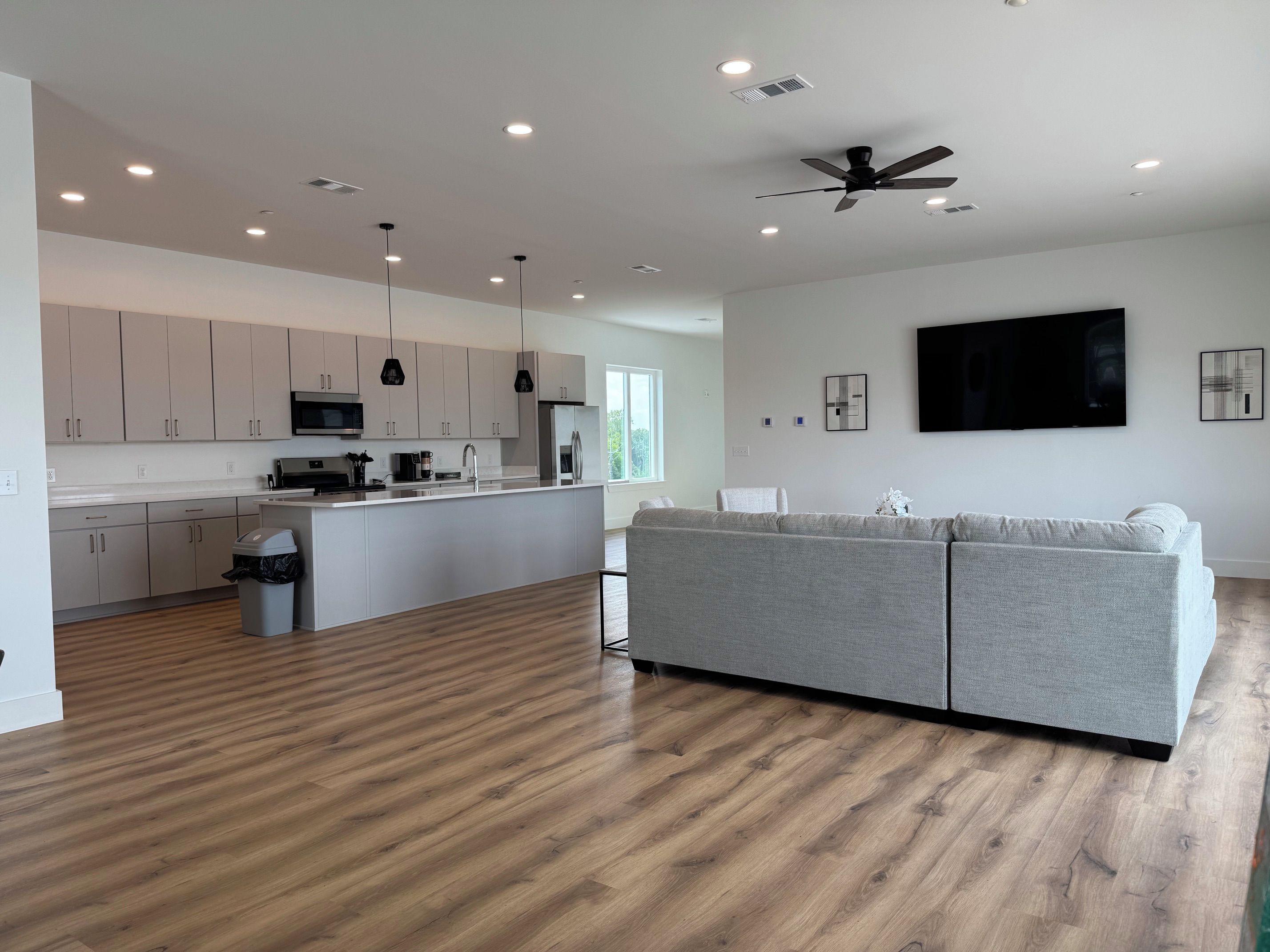 A modern kitchen with white cabinets, a central island, and a ceiling fan.