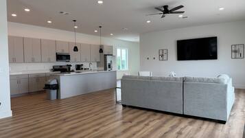 A modern kitchen with white cabinets, a central island, and a ceiling fan.