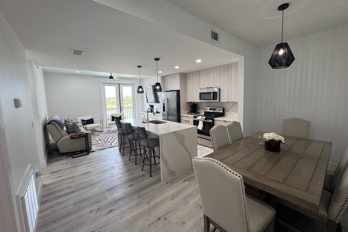 A modern kitchen with a central island, stainless steel appliances, and pendant lighting.