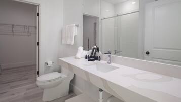 Ein modernes Badezimmer mit Waschbecken, Spiegel und Toilette in Weiß.