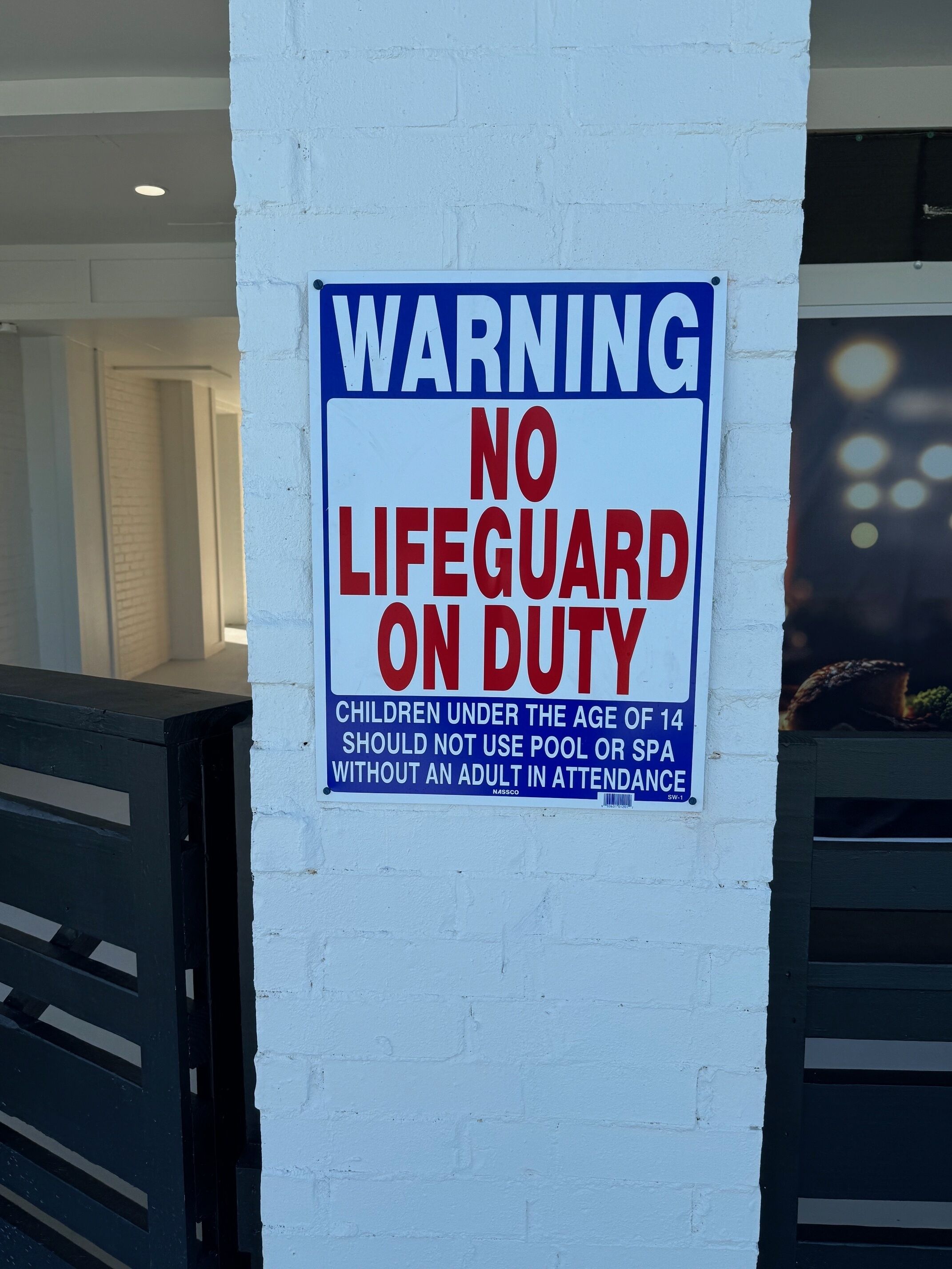 Ein Warnschild an einer weißen Ziegelwand.