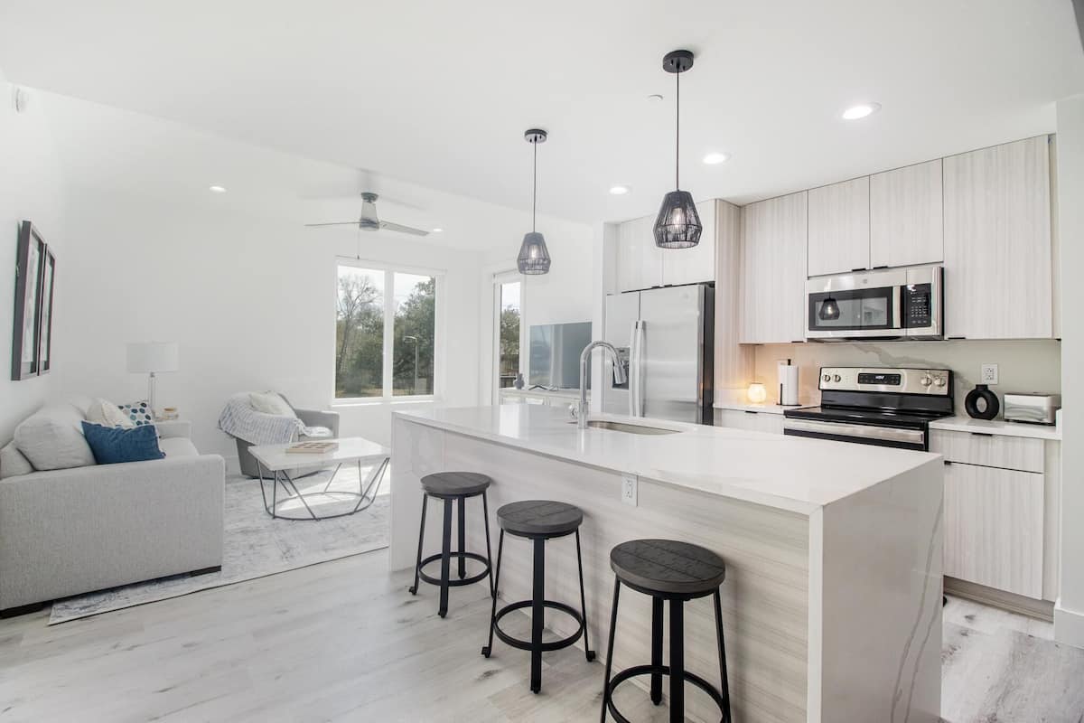 A modern kitchen with a large island, bar stools, and contemporary appliances.