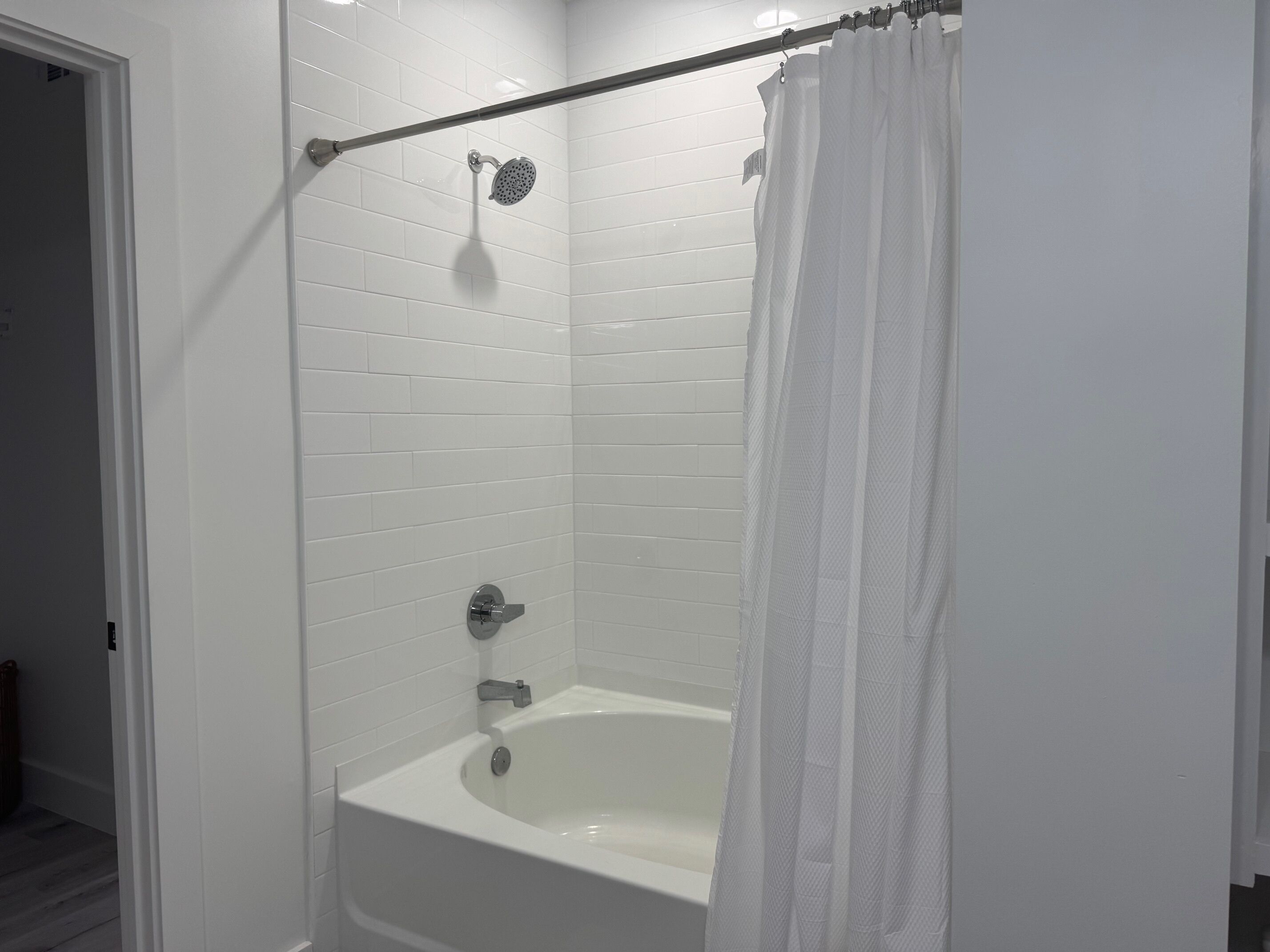 Un baño moderno con una bañera blanca, un cabezal de ducha y una cortina.