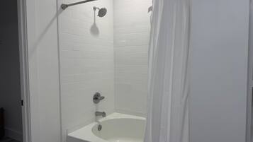 Ein modernes Badezimmer mit einer weißen Badewanne, einer Duschbrause und einem Duschvorhang.