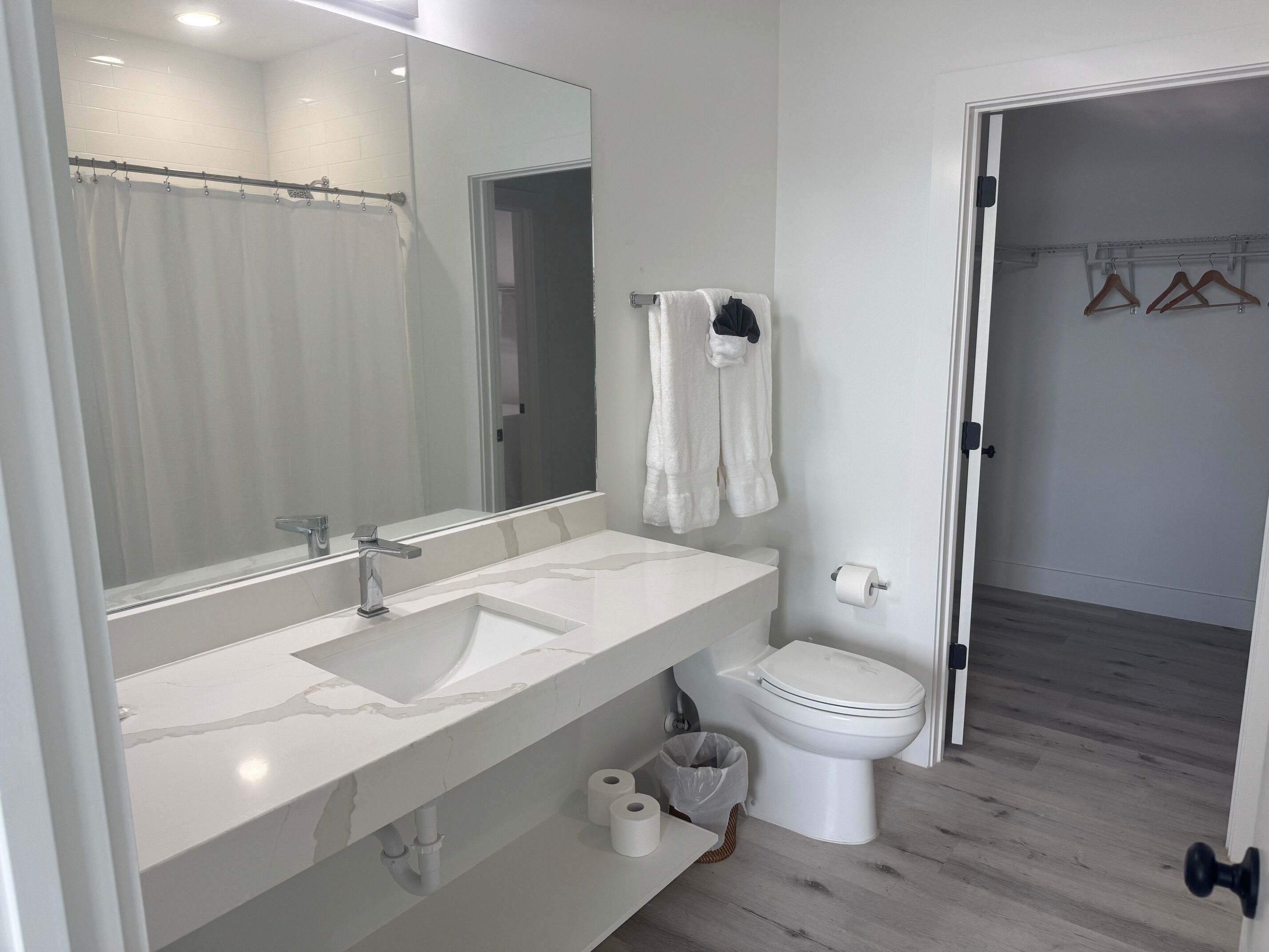 Ein modernes Badezimmer mit Waschbecken, Spiegel und Toilette in Weiß.
