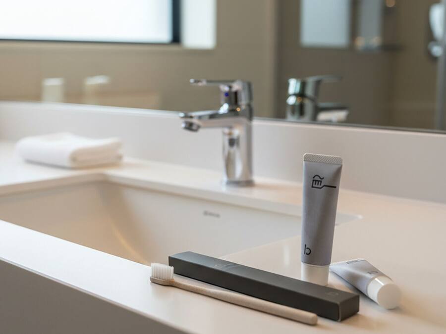 A modern bathroom with a white sink, a mirror, and a toothbrush holder.