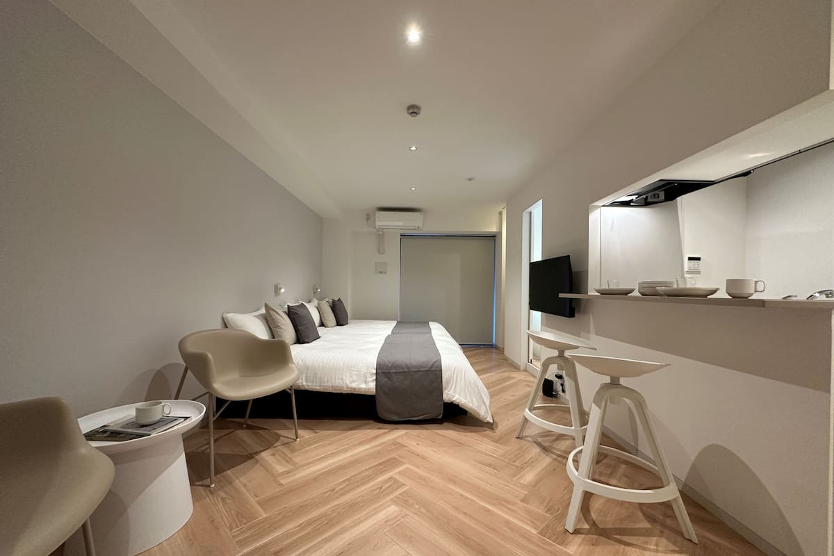 A modern hotel room with a bed, a desk, a chair, and a TV.