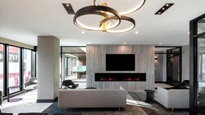 Een moderne hotellobby met een open haard, comfortabele zitplaatsen en een groot televisiescherm.