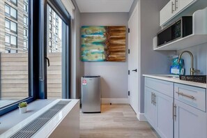 Una cocina moderna con un refrigerador de acero inoxidable, un microondas y un lavamanos.
