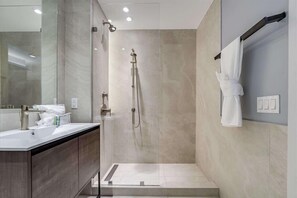 Un baño moderno con cabina de ducha de vidrio, un espejo grande y un perchero para toallas.