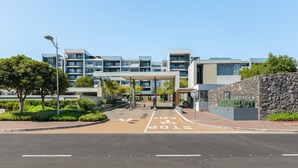 Un bâtiment moderne à plusieurs étages, doté d’un mur en pierre et surplombant un ciel dégagé.