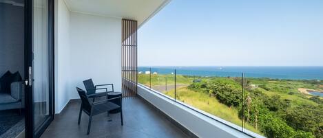A balcony with a view of the ocean and greenery.